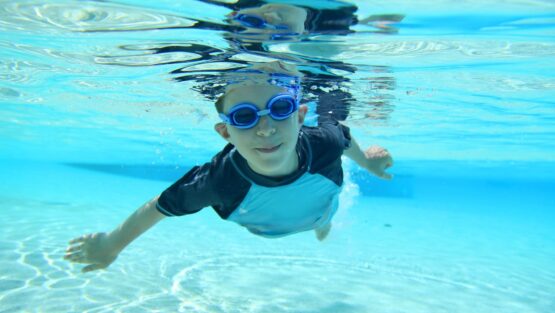 Underwater shot of young boy swimming with goggles on
