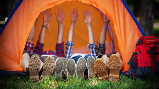 Group of young campres lying down in a tent with their hands up