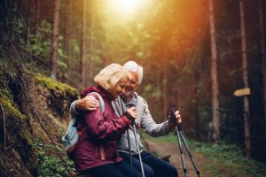 Photo of a senior couple, resting on the bench during the hike through the forest